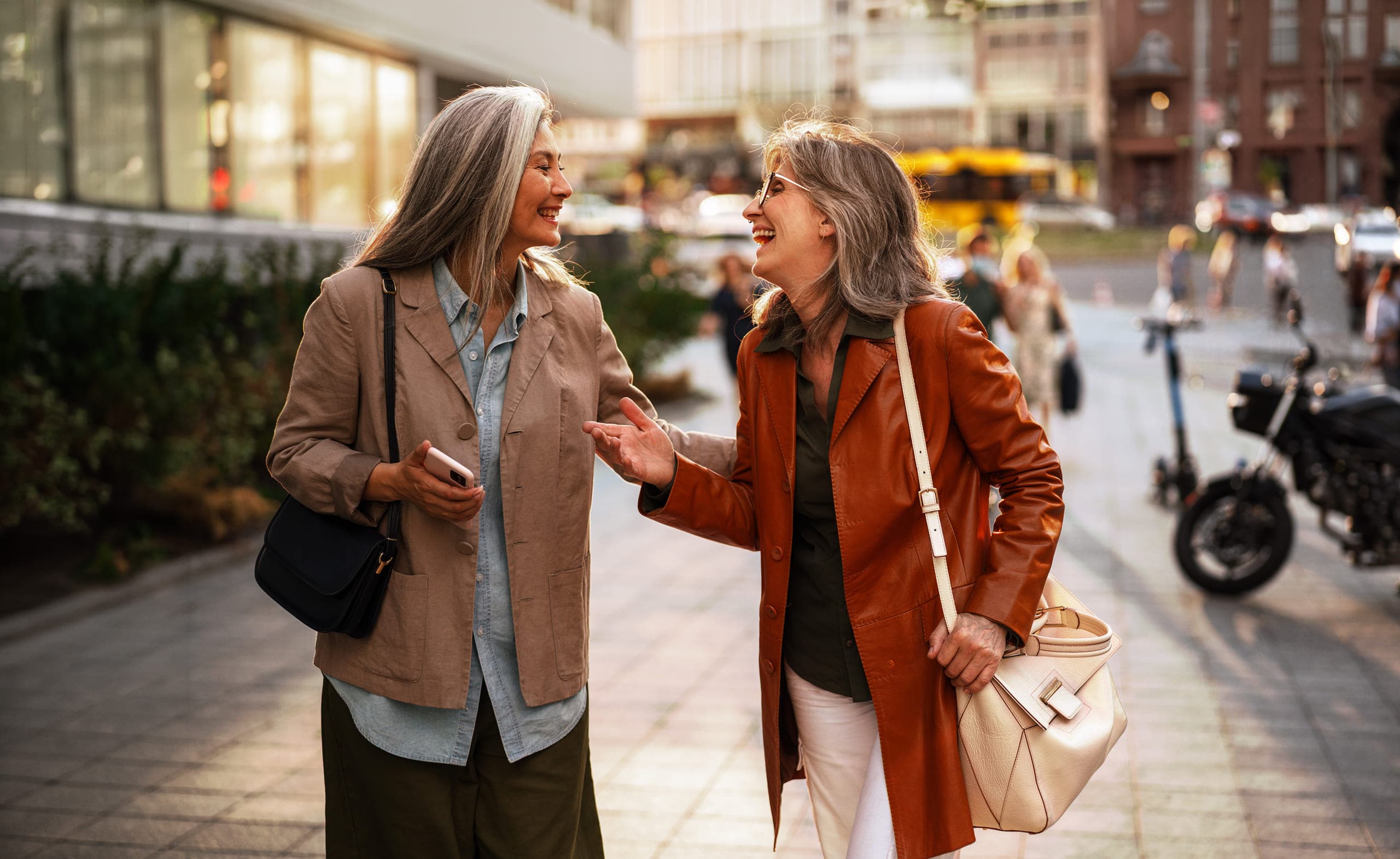 Two women in their fifties walking together outdoors, mid-conversation.